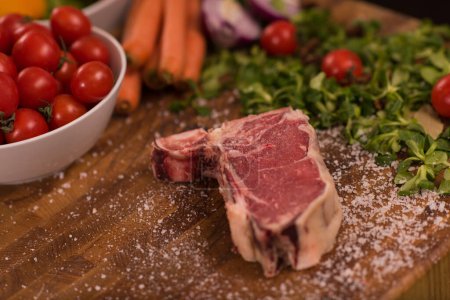 Photo for "Juicy slice of raw steak on wooden table" - Royalty Free Image