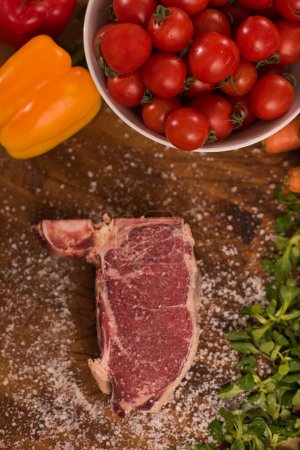Photo for "Juicy slice of raw steak on wooden table" - Royalty Free Image