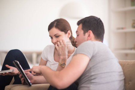 Téléchargez les photos : Couple relaxant à la maison avec tablettes - en image libre de droit