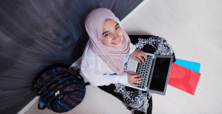 Téléchargez les photos : Arabe étudiante travaillant sur ordinateur portable de la maison - en image libre de droit