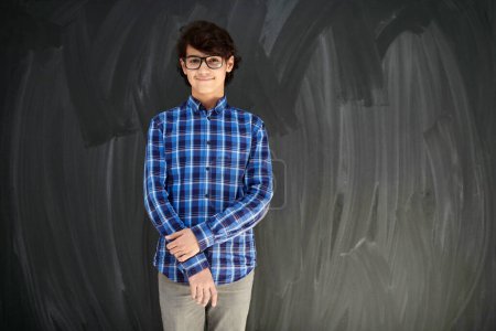 Photo for Portrait  of smart looking arab teenager with glasses against black chalkboard - Royalty Free Image