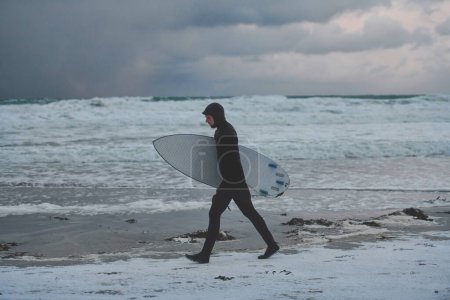Foto de Surfista ártico va por la playa después de surfear - Imagen libre de derechos
