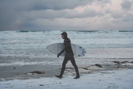 Foto de Surfista ártico va por la playa después de surfear - Imagen libre de derechos