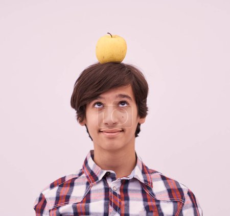 Foto de Retrato de un joven adolescente con una manzana en la cabeza - Imagen libre de derechos