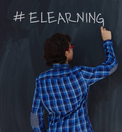 Téléchargez les photos : Adolescent garçon avec craie écriture sur tableau de bord noir hashtag elearning - en image libre de droit