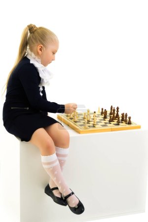 Téléchargez les photos : Petite fille jouant aux échecs. Isolé sur fond blanc - en image libre de droit
