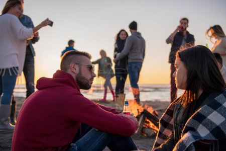 Photo for Couple enjoying with friends on beach at sunset - Royalty Free Image