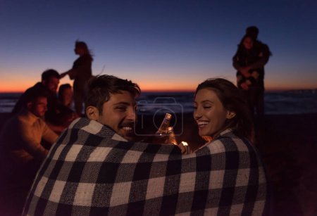 Téléchargez les photos : Couple profiter avec des amis sur la plage au coucher du soleil - en image libre de droit