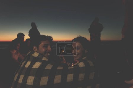 Photo for Couple enjoying with friends on beach at sunset - Royalty Free Image