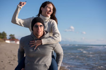 Téléchargez les photos : "couple s'amuser à la plage pendant l'automne" - en image libre de droit