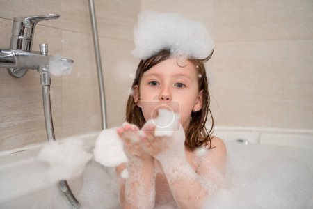 Photo for Little girl in bath playing with foam - Royalty Free Image