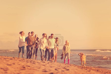 Foto de Grupo de amigos corriendo en la playa durante el día de otoño - Imagen libre de derechos