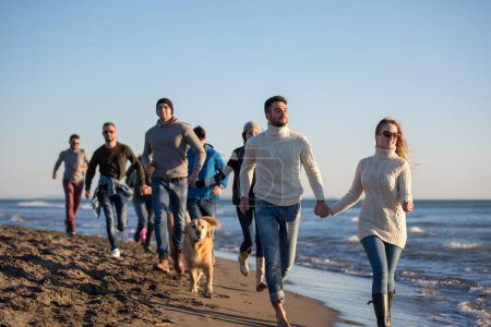 Photo for Group of friends running on beach during autumn day - Royalty Free Image