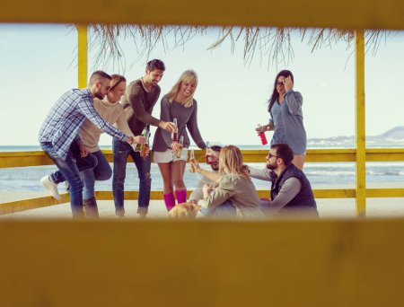 Téléchargez les photos : Groupe d'amis s'amuser le jour d'automne à la plage - en image libre de droit