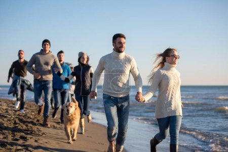 Foto de Grupo de amigos corriendo en la playa durante el día de otoño - Imagen libre de derechos