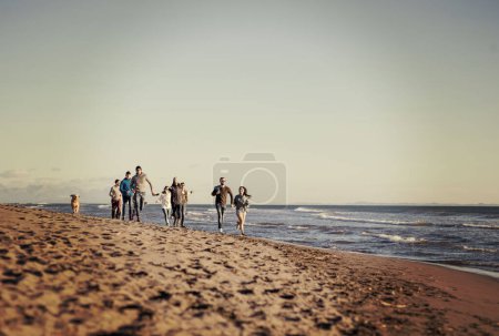Photo for Group of friends running on beach during autumn day - Royalty Free Image