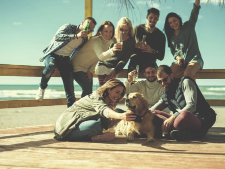 Téléchargez les photos : Groupe d'amis s'amuser le jour d'automne à la plage - en image libre de droit