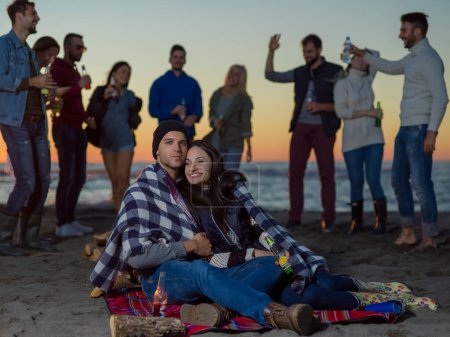 Téléchargez les photos : "Couple profiter avec des amis au coucher du soleil sur la plage" - en image libre de droit