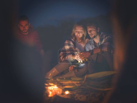 Téléchargez les photos : Couple profiter avec des amis la nuit sur la plage - en image libre de droit