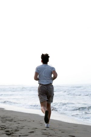 Téléchargez les photos : Homme courant sur la plage - en image libre de droit
