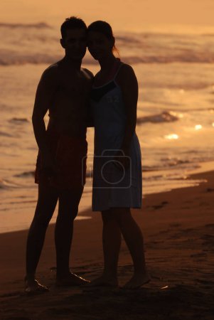 Foto de Pareja joven enamorada al atardecer en la playa - Imagen libre de derechos