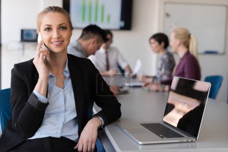 Foto de "mujer de negocios hablando por teléfono en la oficina con el equipo en la reunión en segundo plano" - Imagen libre de derechos