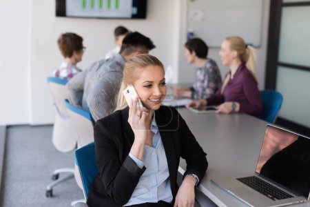 Photo for "business woman speeking on phone at office with team on meeting in background" - Royalty Free Image