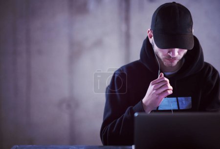 Téléchargez les photos : Hacker talentueux en utilisant un ordinateur portable tout en travaillant dans le bureau sombre - en image libre de droit