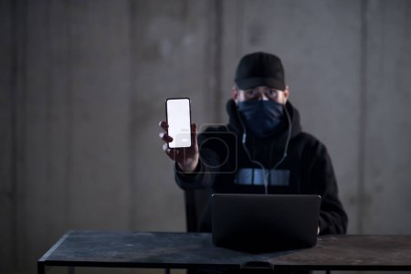 Photo for Criminal hacker using laptop computer while working in dark office - Royalty Free Image