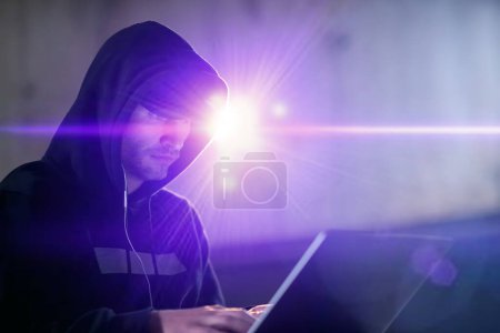 Foto de Joven hacker talentoso utilizando el ordenador portátil mientras trabaja en la oficina oscura - Imagen libre de derechos