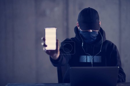 Photo for Criminal hacker using laptop computer while working in dark office - Royalty Free Image