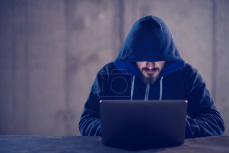 Téléchargez les photos : Hacker talentueux en utilisant un ordinateur portable tout en travaillant dans le bureau sombre - en image libre de droit