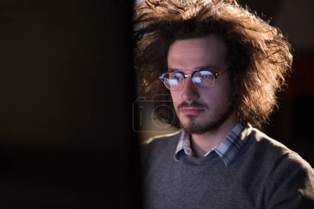 Photo for "man working on computer in dark office" - Royalty Free Image