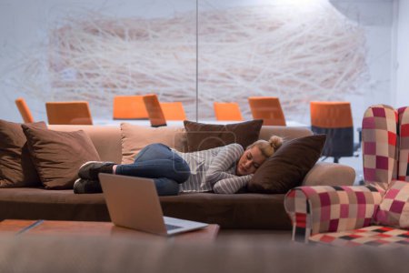 Foto de Mujer durmiendo en un sofá en una oficina creativa - Imagen libre de derechos