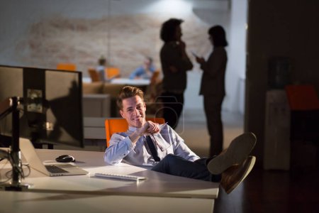 Téléchargez les photos : Jeune homme d'affaires assis avec les jambes sur le bureau au bureau - en image libre de droit