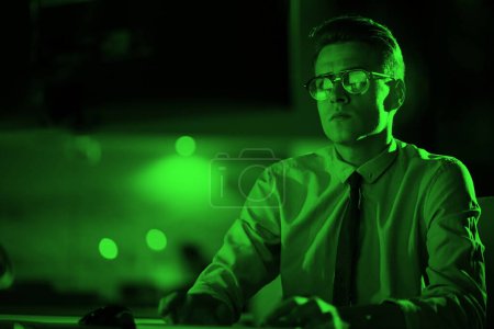 Photo for "man working on computer in dark office" - Royalty Free Image