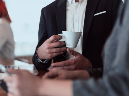 Téléchargez les photos : Macro photo d'un homme d'affaires dans un café en costume tenant une tasse de café. - en image libre de droit