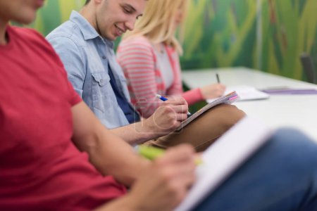 Photo for Male student taking notes in classroom - Royalty Free Image
