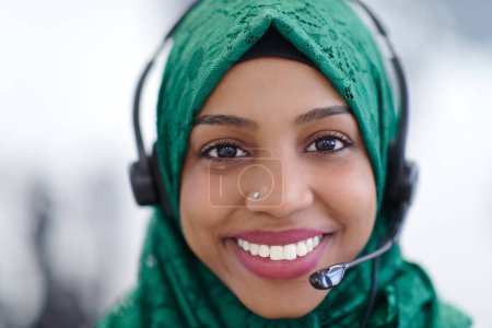 Téléchargez les photos : Femme musulmane africaine avec casque téléphonique aidant et soutenant en ligne - en image libre de droit