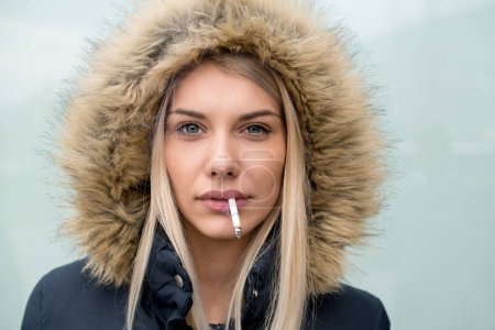 Téléchargez les photos : Portrait de jeune fille blonde avec cigarette dans la bouche - en image libre de droit