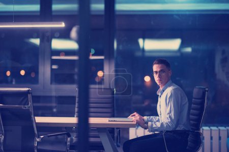 Photo for Man working on laptop in dark office - Royalty Free Image