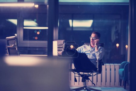 Photo for "businessman using mobile phone in dark office" - Royalty Free Image