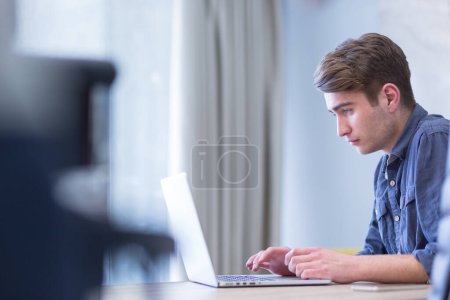 Téléchargez les photos : "homme d'affaires travaillant en utilisant un ordinateur portable dans le bureau de démarrage
" - en image libre de droit