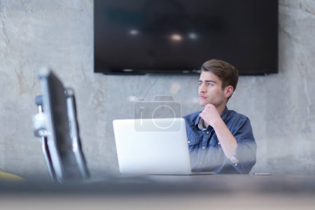 Téléchargez les photos : "homme d'affaires travaillant en utilisant un ordinateur portable dans le bureau de démarrage
" - en image libre de droit