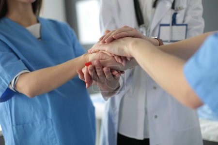 Téléchargez les photos : "Médecin et infirmières dans une équipe médicale empilant les mains" - en image libre de droit