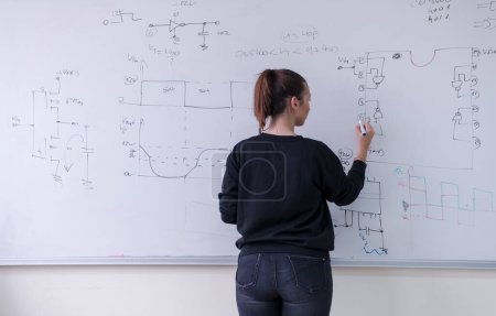 Photo for Female student writing on board in classroom - Royalty Free Image