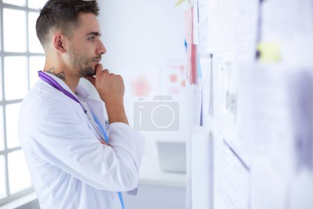 Téléchargez les photos : "Jeune et confiant portrait de médecin masculin debout dans le bureau médical." - en image libre de droit