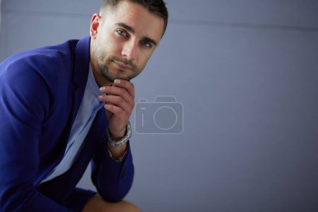 Téléchargez les photos : Jeune homme d'affaires assis isolé sur fond gris. - en image libre de droit
