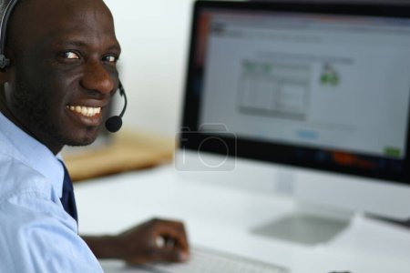 Foto de "Hombre de negocios afroamericano con auriculares trabajando en su computadora portátil" - Imagen libre de derechos