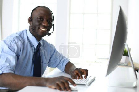 Téléchargez les photos : Homme d'affaires afro-américain sur casque de travail sur son ordinateur portable - en image libre de droit